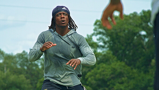 Athlete in a focused, athletic ready stance training outdoors on a summer day.